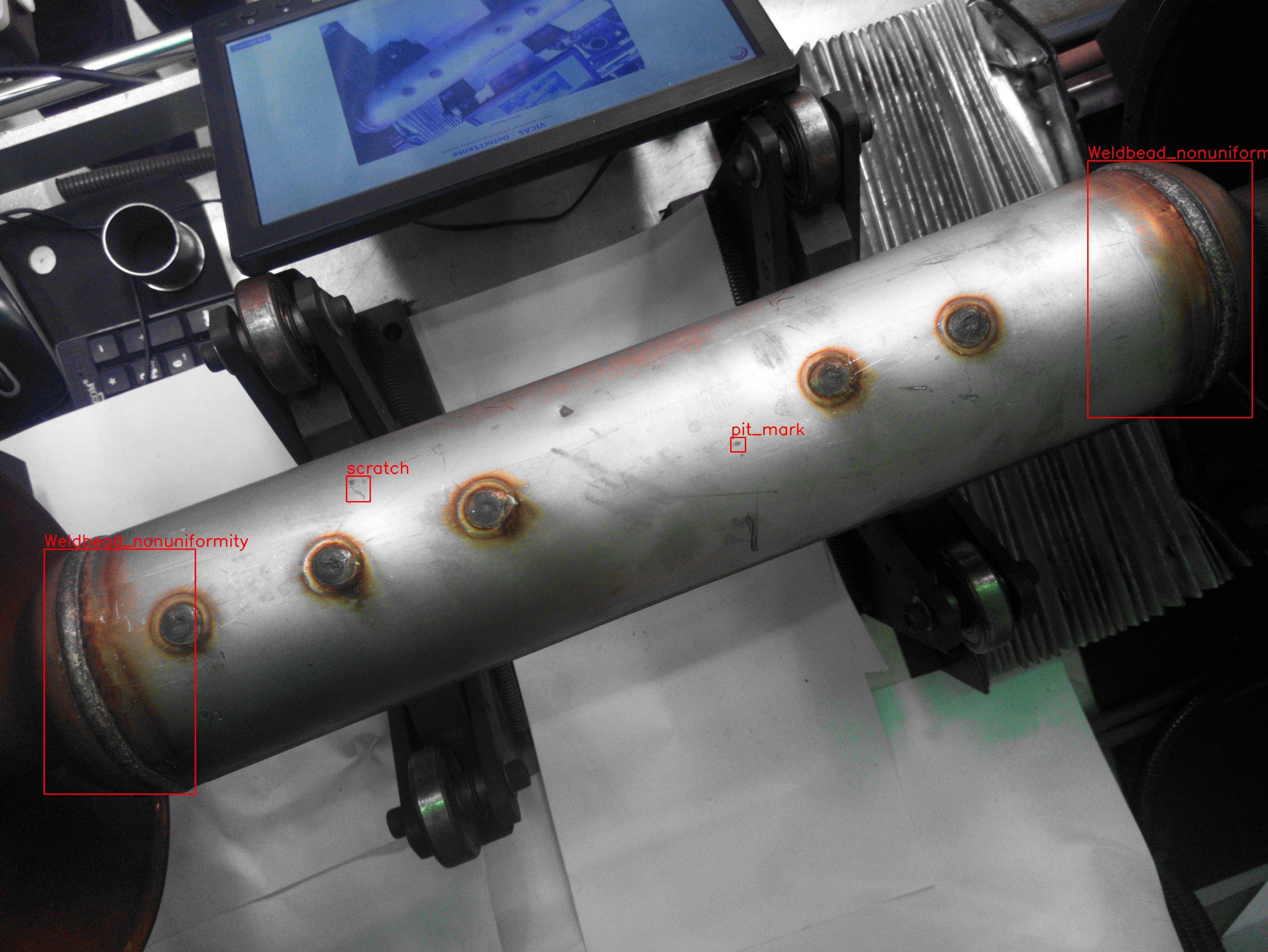 Detection view of a welded exhaust component with weld-bead nonuniformity, pit mark and scratch regions boxed