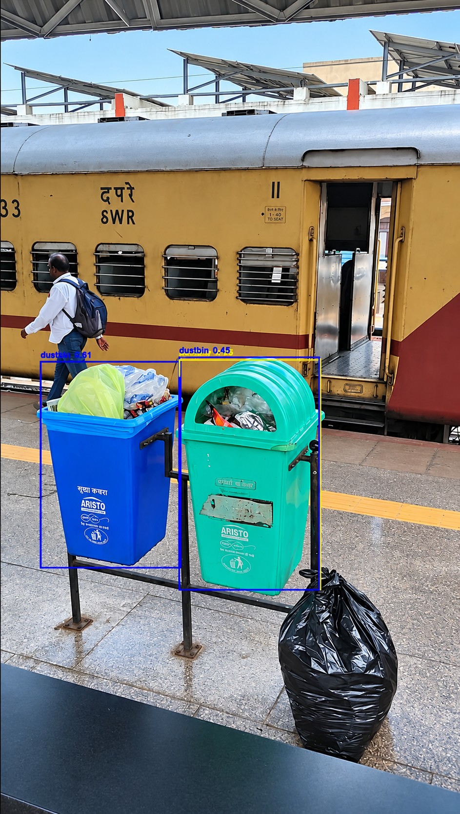 Two platform dustbins detected and boxed, both overflowing with waste