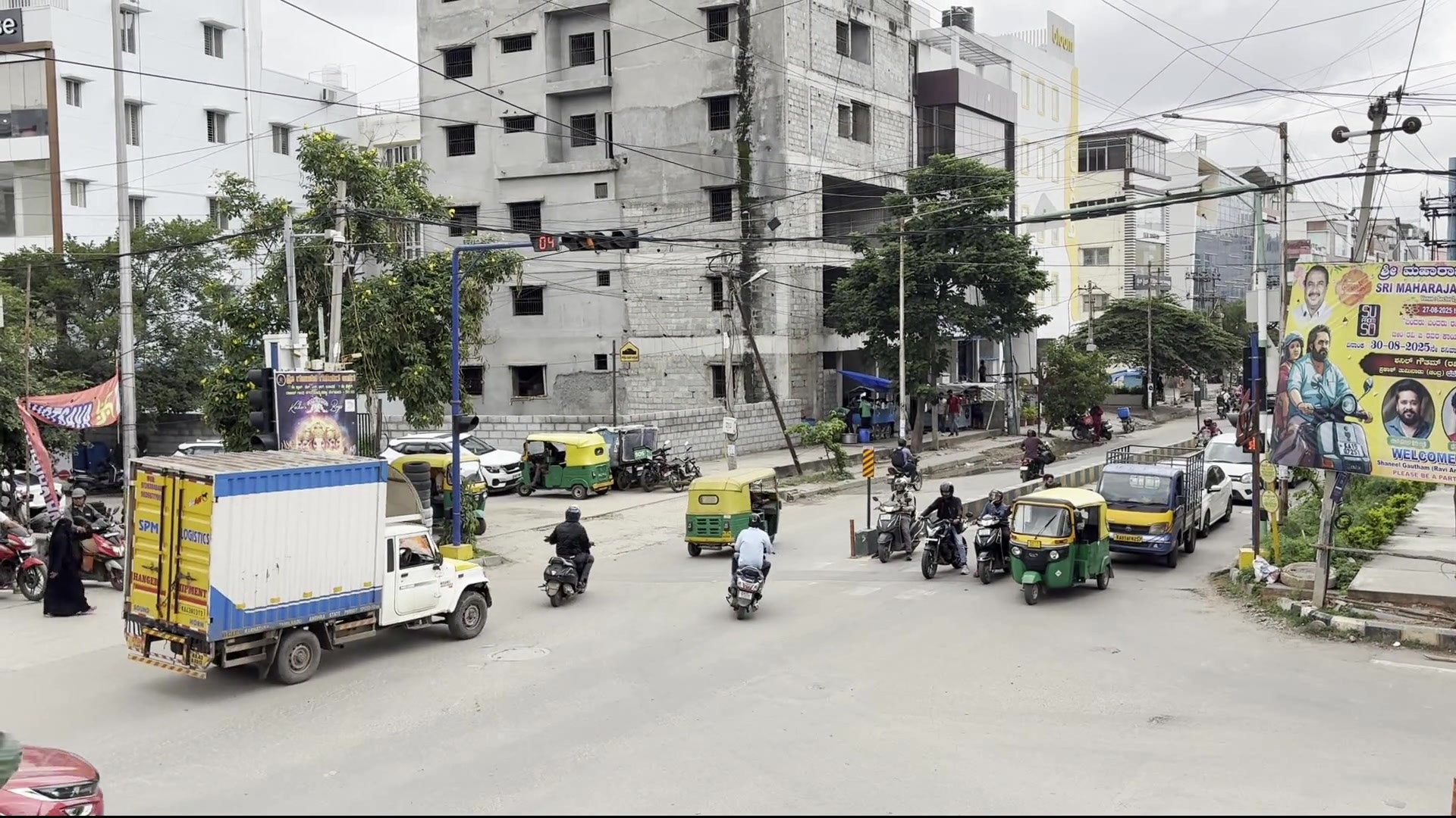 Wide multi-lane junction with autos, bikes, a truck and cars moving through at once